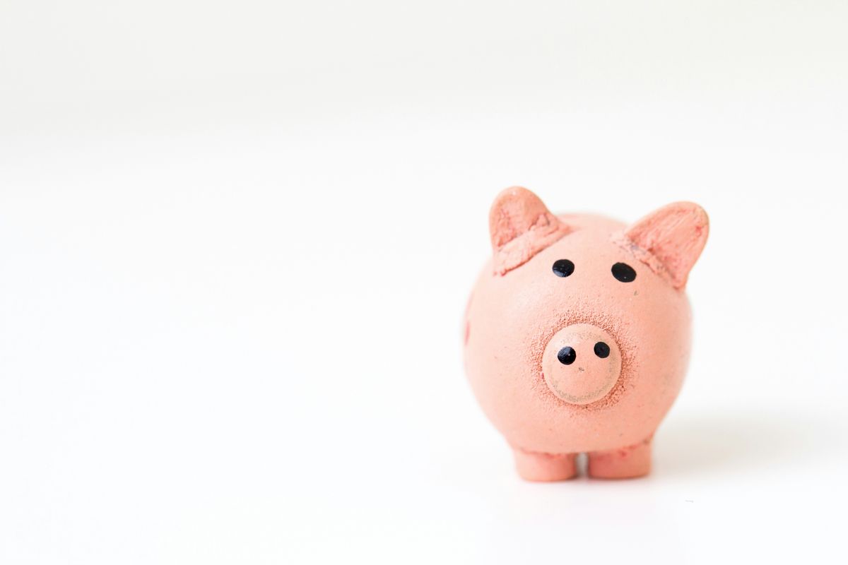 A small, pink piggy bank with visible ears, eyes, and snout on a plain white background.